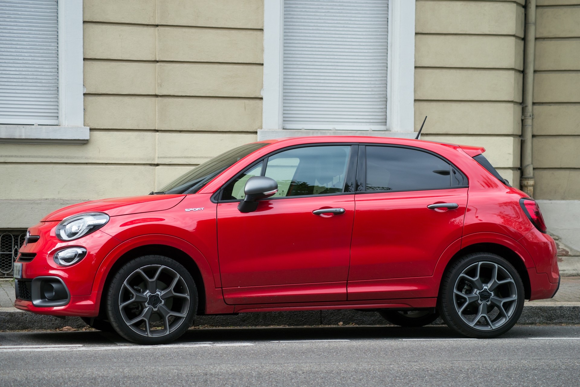 Vista profilo della Fiat 500X rossa parcheggiata in strada